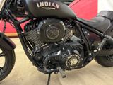 a black motorcycle parked in a garage with a red wall in the background