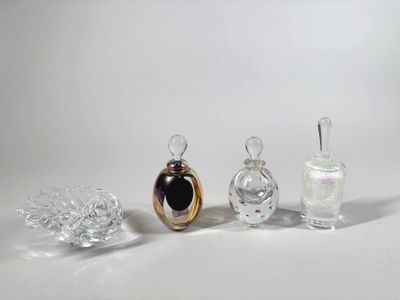 trois flacons de parfum en verre posés les uns à côté des autres sur une surface blanche