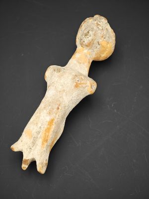 une figurine antique représentant une femme coiffée d'un chapeau