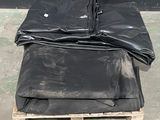 une pile de bâches noires posée sur une palette en bois