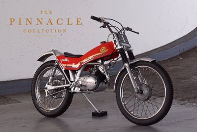 a red motorcycle parked in front of the pinnacle collection sign