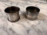two silver cups sitting on a marble counter top