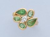 gros plan d'une bague en or avec des pierres vertes et blanches