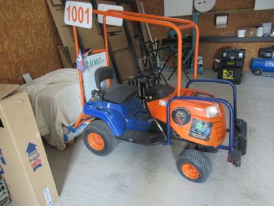 un petit tracteur bleu et orange garé dans un garage