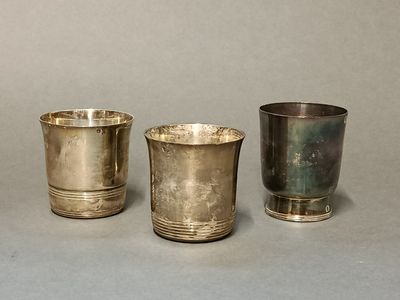trois tasses en argent posées l'une à côté de l'autre sur une table