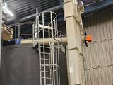 a large metal tank in a warehouse with a ladder