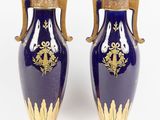 une paire de vases bleus et dorés posés sur une surface blanche