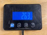 a digital clock on a wooden table with a cord