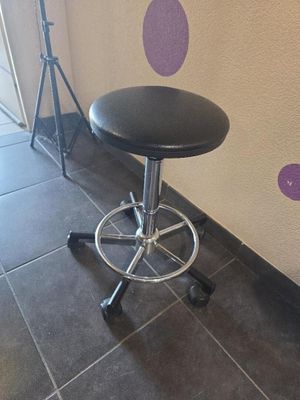 un tabouret noir posé devant un mur à pois