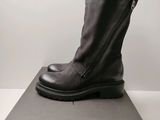 Des bottes en cuir noir avec des fermetures éclair sont posées sur une boîte