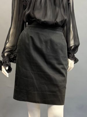 un mannequin vêtu d'une jupe en cuir noir et d'un chemisier transparent