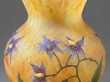 un vase jaune sur lequel sont peintes des fleurs violettes