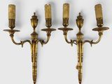 three antique brass wall sconces with candles on each of them
