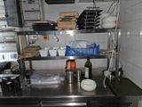 un plan de travail en acier inoxydable dans une cuisine, sur lequel sont posés de la vaisselle et des ustensiles