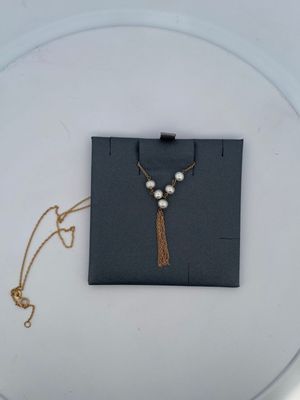 collier composé de perles et d'une chaîne en or, présenté sur une assiette blanche