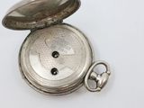 a silver pocket watch sitting on top of a white table