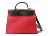un sac à main rouge et noir posé sur une surface blanche