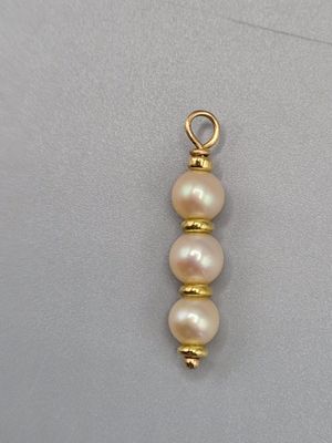 un gros plan d'un pendentif plaqué or orné de trois perles
