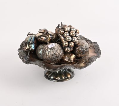 un bol en argent rempli d'objets décoratifs en argent, posé sur une surface blanche