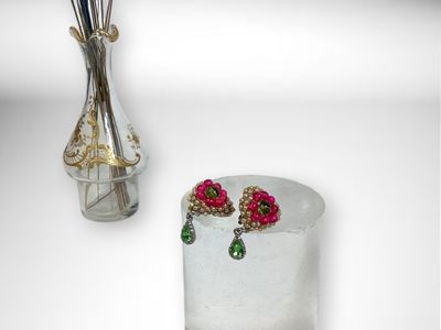 a vase with flowers in it next to a pair of earrings