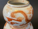 a white and orange vase with a dragon on it