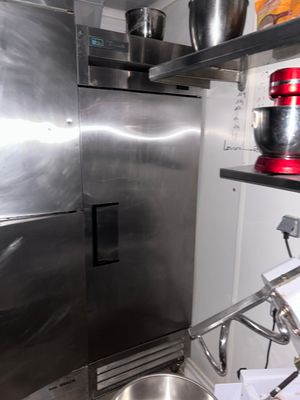 a stainless steel refrigerator in a kitchen with pots and pans on the shelves