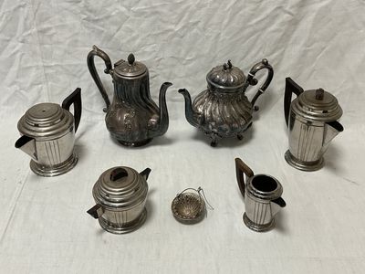 de nombreuses théières et tasses en argent posées sur une table