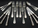 a lot of forks and spoons on a black table