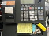 une calculatrice posée sur un bureau recouvert d'une pile de papiers