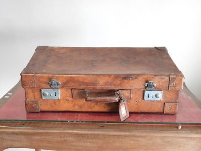 une valise marron posée sur une table en verre