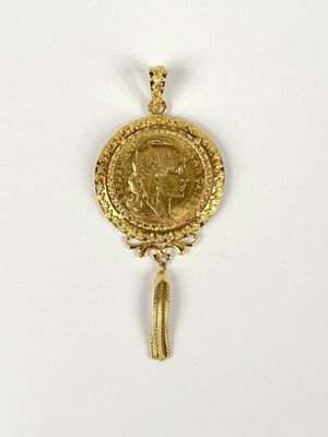 a close up of a gold coin with a tassel on a white surface