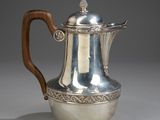 an antique silver coffee pot with a wooden handle on a grey background
