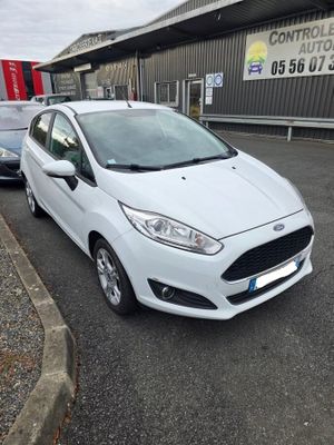 une Ford Fiesta blanche garée devant un immeuble