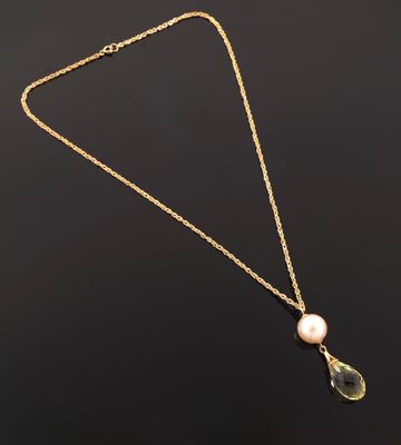a gold necklace with a pearl and a pendant on it