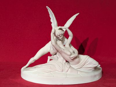 statue représentant une femme agenouillée sur un homme ailé, sur fond rouge