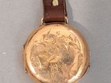 a gold watch with a picture of a horse on it