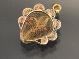 an image of a gold pendant on a black surface