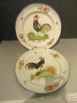 deux assiettes ornées de coqs, exposées