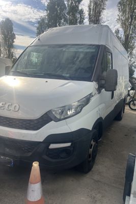 La camionnette blanche est garée à côté d'un cône de signalisation sur le parking.