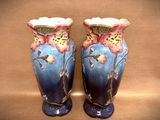 two blue vases with flowers on them on a table