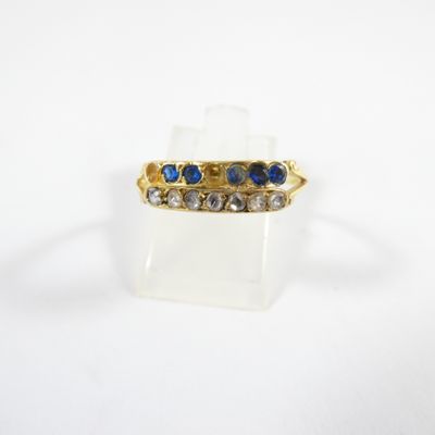 gros plan d'une bague en or avec des pierres bleues et blanches