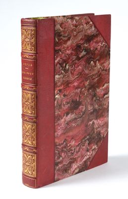 an old book with a red cover sitting on top of a white surface