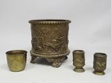 three brass vases and a cup on a white background