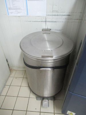a trash can sitting next to a refrigerator in a kitchen