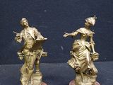pair of antique bronze figurines of a woman and a man on a horse