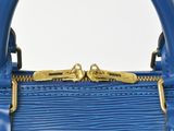 a close up of a blue handbag with a gold handle