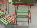 three green and red folding chairs sitting in a warehouse area