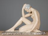 statue d'une femme assise sur un socle de marbre, la tête entre les mains