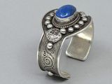 a close up of a silver cuff with a blue stone on it