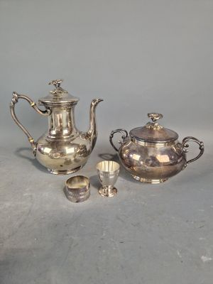 trois théières et tasses en argent posées sur une table devant un fond gris